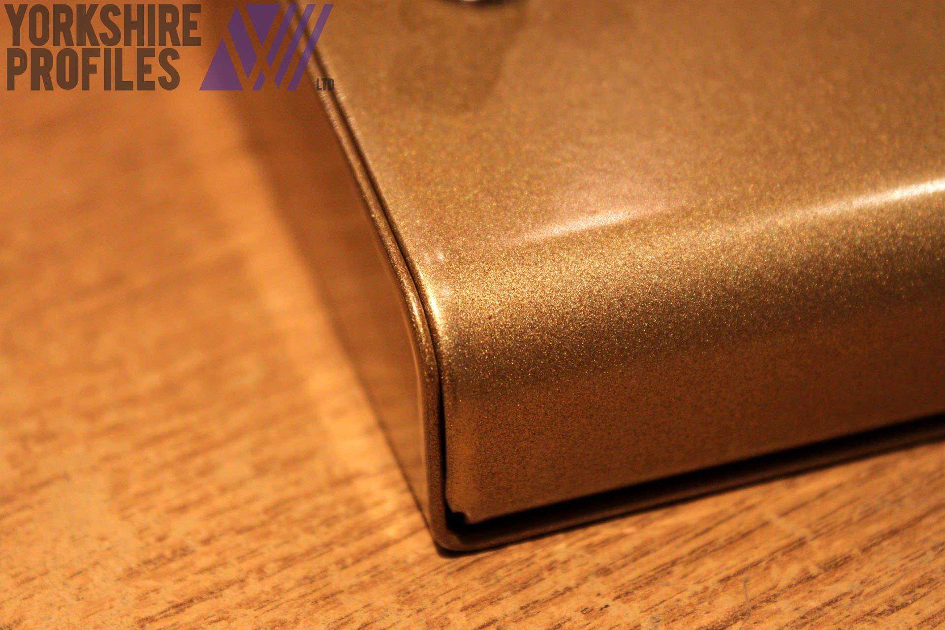 A close up of a radius bend with metallic gold powder-coating.