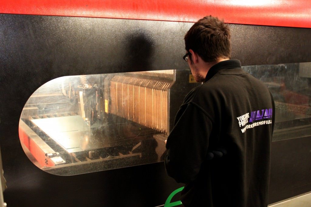 Laser operator monitors laser cutting equipment